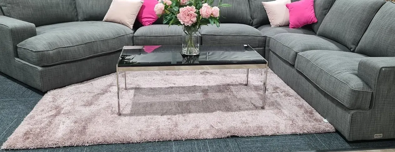 Soft pink rug and coffee table set between grey lounge suites in store - Whitehouse Furnishers, Katherine