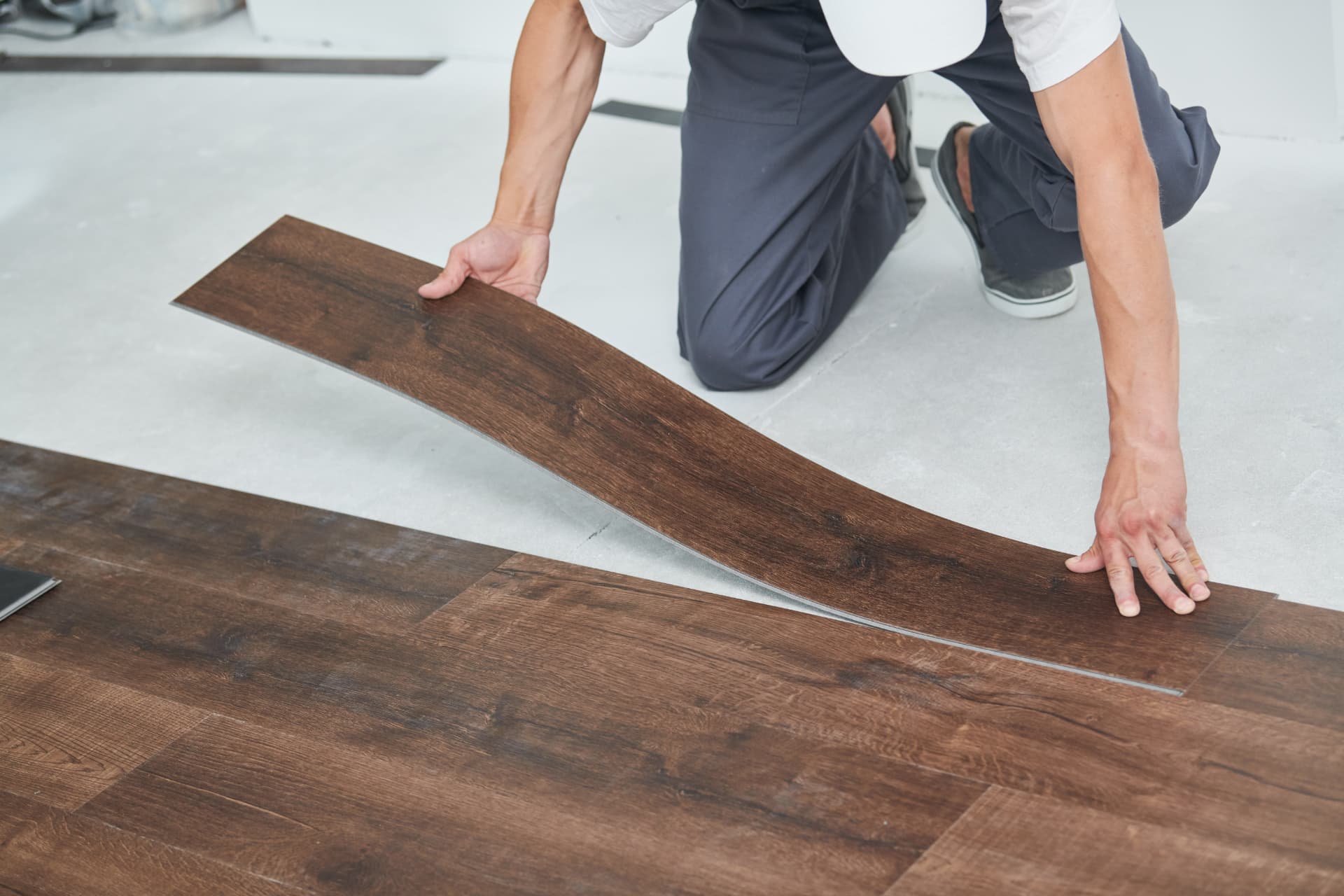 Installer laying dark timber-look vinyl plank flooring in a home - Whitehouse Furnishers, Katherine