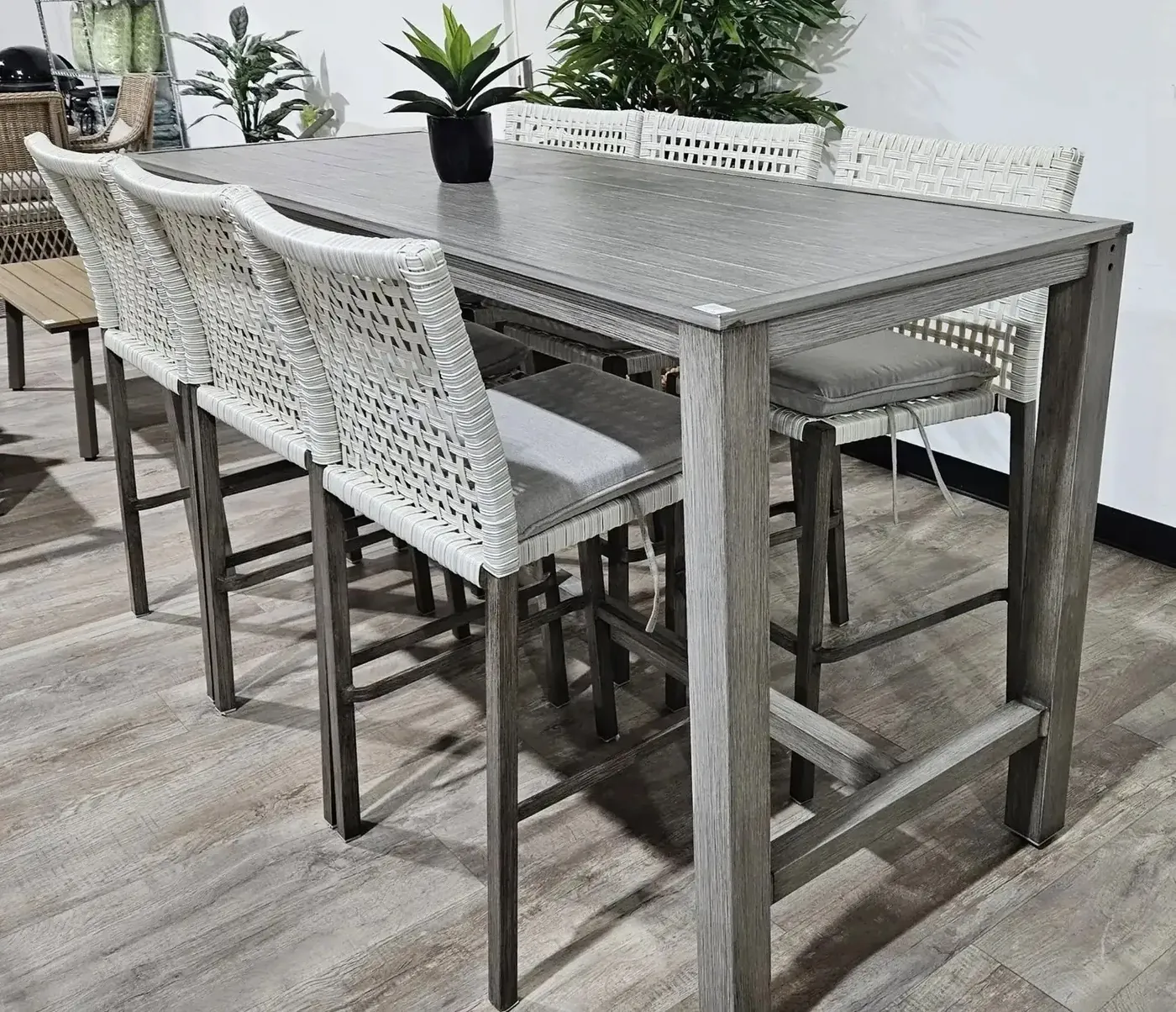 Timber dining table with woven bar stools on display in the Whitehouse Furnishers showroom